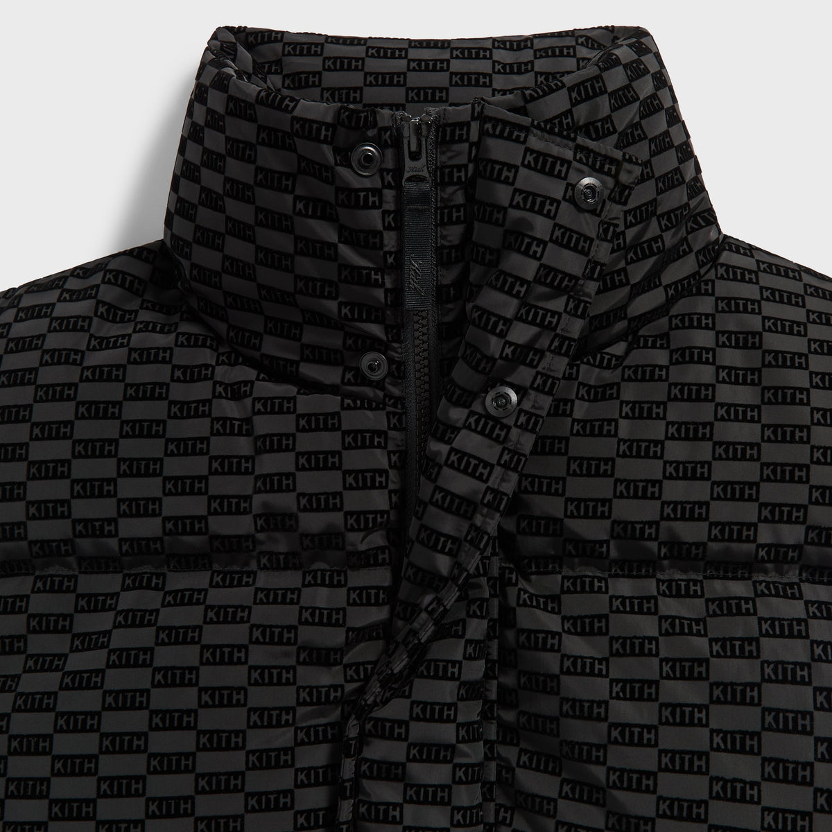 Close-up of the stand collar, zip and tonal KITH monogram flocking on the black Westley puffer