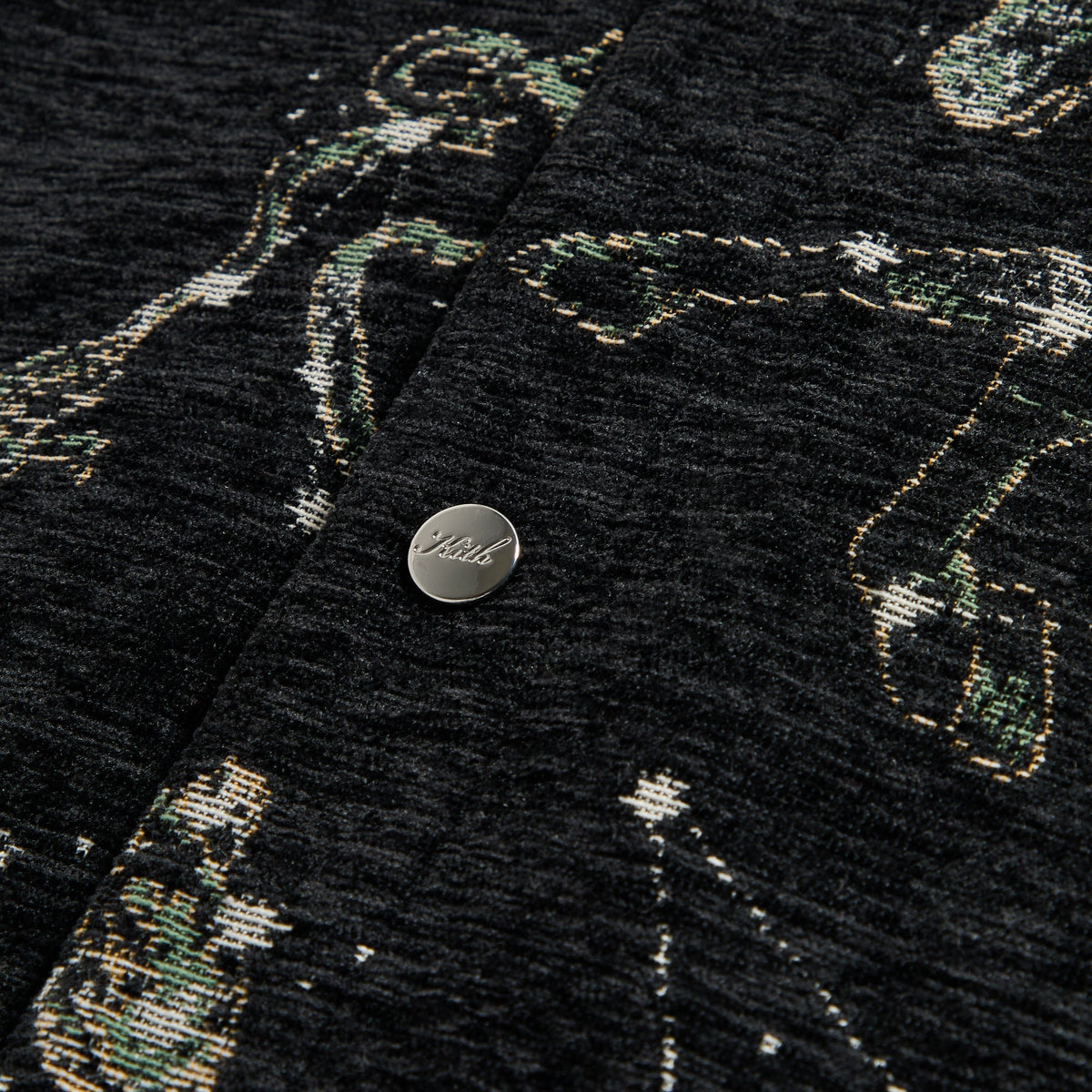 Close-up of a silver Kith snap button on the black Chenille Tapestry Helios jacket