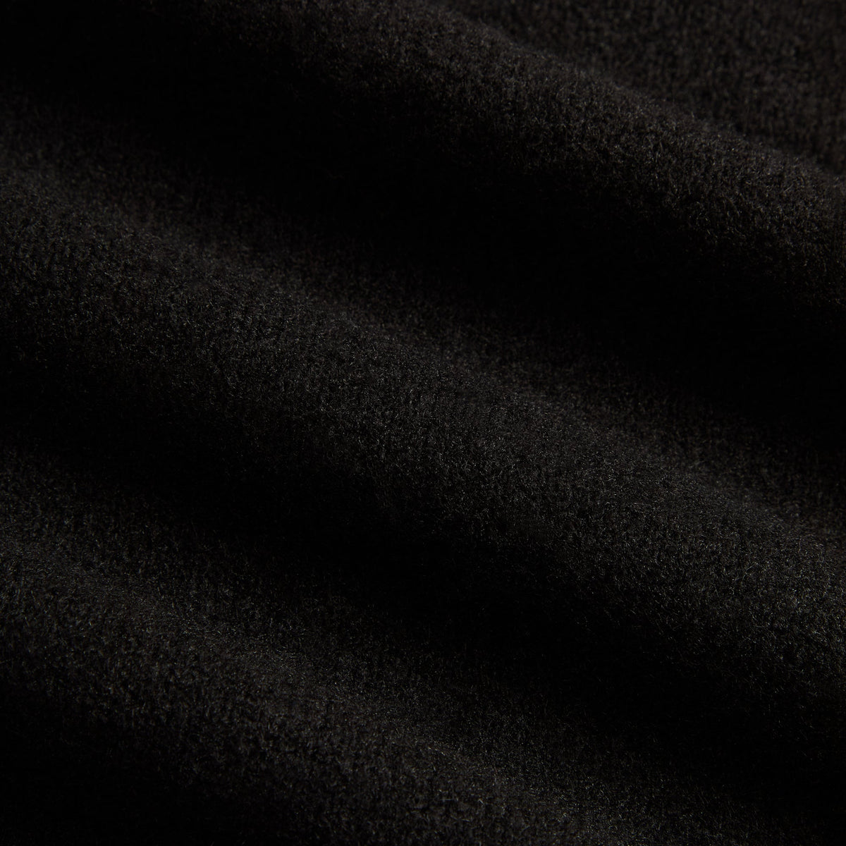 Close-up of black knit fabric of the Kith Harmon henley sweater