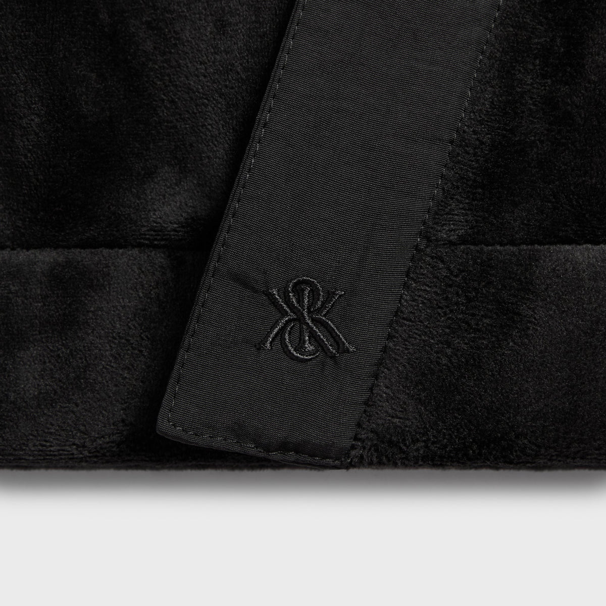 Close-up of the &Kin logo on the sash of the black Plush Double Fleece Strauss cardigan