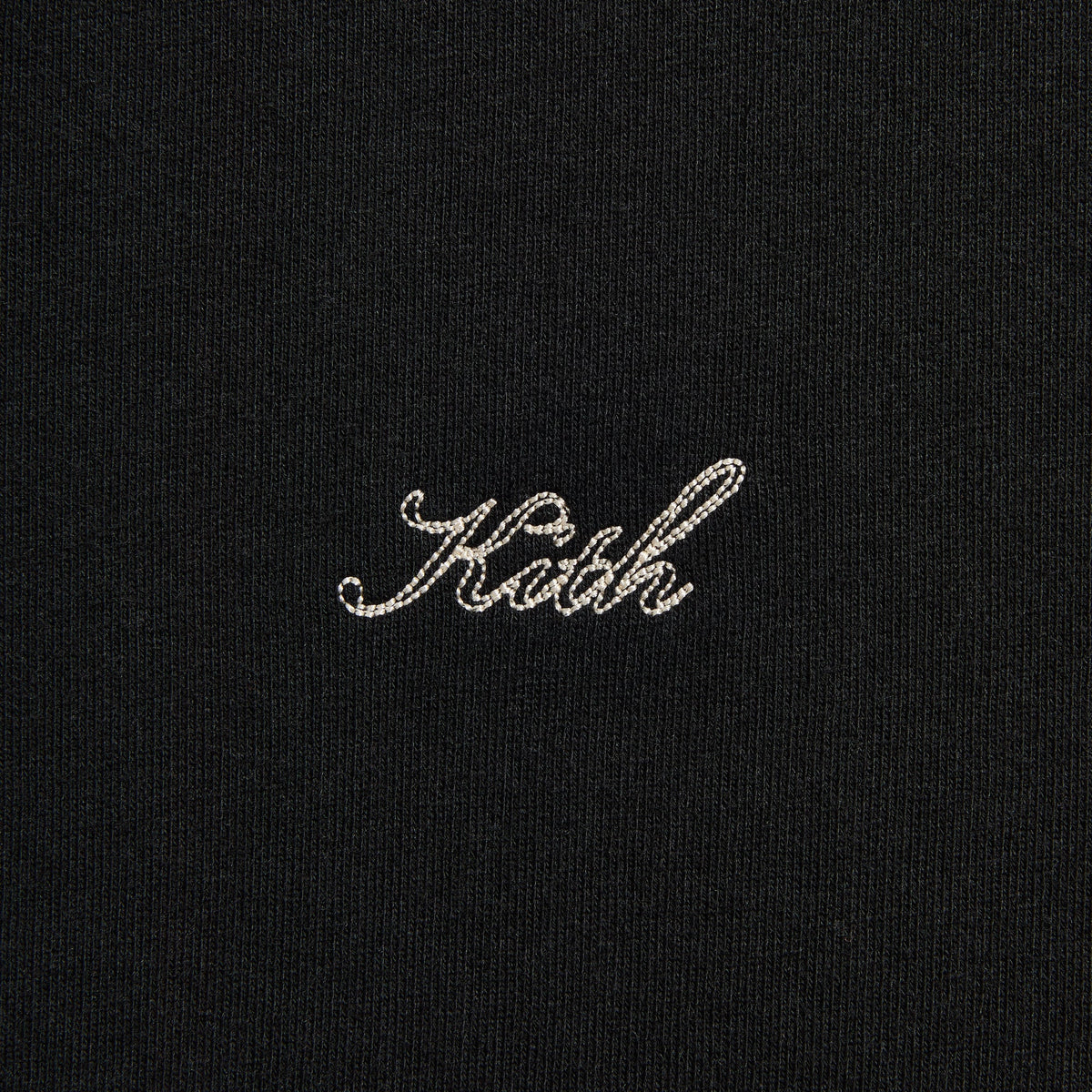 Close-up of the white 'Kith' script on the black Thermal Lined Fleece Tobias zip hoodie